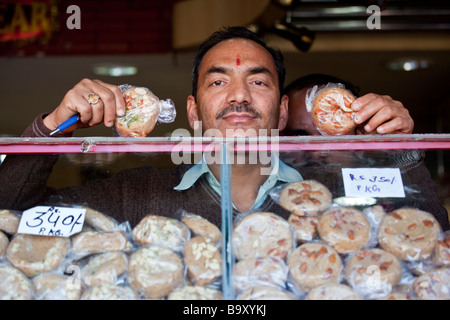 Propriétaire de Sweet Shop Ghantewala affichant sa fameuse Sohan Halwa ou plaqués de cajou dans la région de Old Delhi Inde Banque D'Images