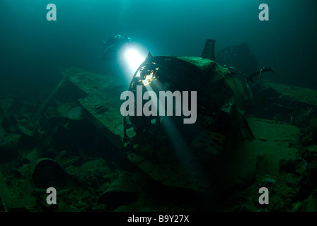 Un plongeur fait briller leur lumière à travers les trous dans le fuselage d'un avion de chasse zéro japonais dans la soute de l'Fujikawa Maru Banque D'Images