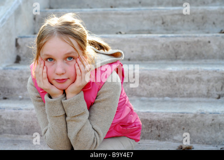 Jeune fille assise sur un escalier en béton de la pensée Banque D'Images