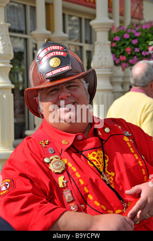 Pompier en chemise rouge à Walt Disney le Parc à Thème Magic Kingdom Orlando Floride fire fighter Central mâle caucasien homme blanc Banque D'Images