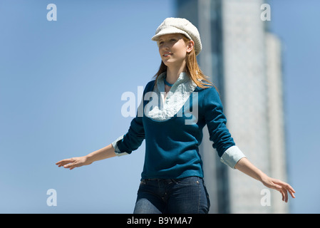 Jeune femme portant un chapeau, branché à l'extérieur permanent avec les bras Banque D'Images