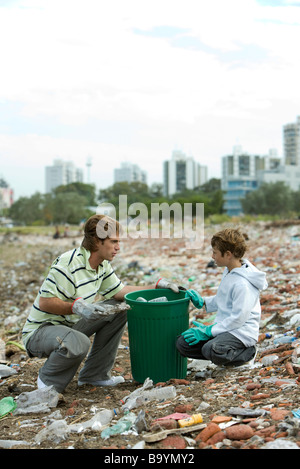 Jeune homme et garçon ramasser des matériaux recyclables dans les déchets heap Banque D'Images