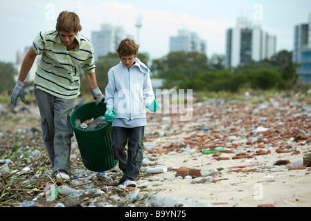 Jeune homme et garçon la collecte de matériaux recyclables dans la poubelle Banque D'Images