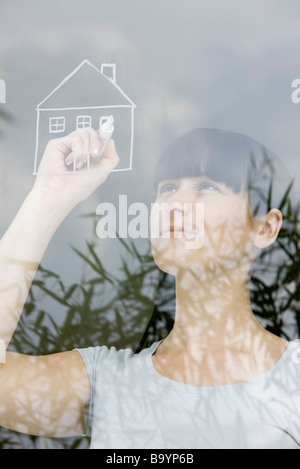 Jeune femme dessin maison sur glace, daydreaming Banque D'Images