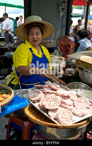 Une heureuse femme thaïlandaise frire des gâteaux de riz sur son stand de Bangkok Thaïlande Banque D'Images