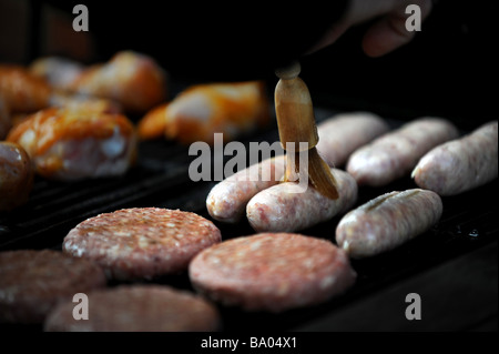 Beefburgers, saucisses, poulet et faire cuire sur un barbecue à gaz Banque D'Images