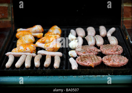 Beefburgers, saucisses, poulet et faire cuire sur un barbecue à gaz Banque D'Images