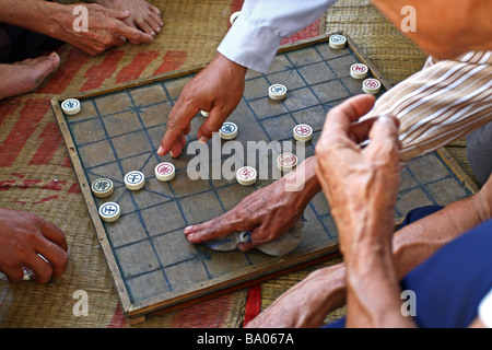 Scène de rue. Close up. Les mains des hommes jouant aux échecs assis sur le sol. Vietnam Banque D'Images