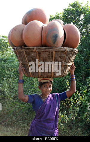 Femme indienne transportant un grand panier plein d'argile des casseroles sur la tête, l'état d'Orissa Banque D'Images