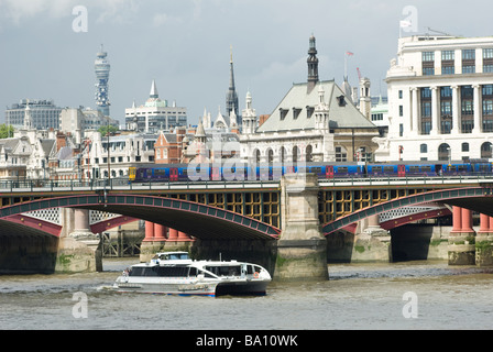 En train First Capital Connect livery crossing blackfriars pont de chemin de fer qu'un bateau passe sous Thames Clipper. Banque D'Images