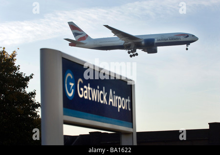 Les roues d'atterrissage sont vers le bas comme un British Airways Jet Airplane lands au-dessus de la gare à l'aéroport de Gatwick. Banque D'Images