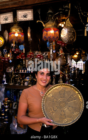 Une femme tenant un marchand bac en cuivre à l'extérieur de son magasin de souvenirs dans la vieille ville de Byblos, Liban Banque D'Images