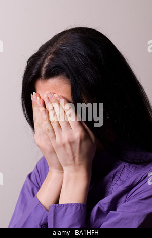 Jeune femme pleurer la tête dans les mains Banque D'Images