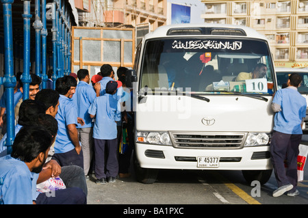 Les travailleurs étrangers de monter dans un bus après une journée de travail Dubaï ÉMIRATS ARABES UNIS Banque D'Images