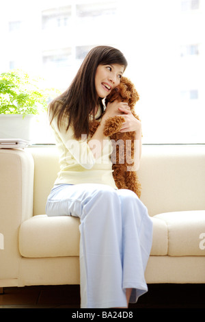 Young woman holding Toy Poodle sur canapé Banque D'Images