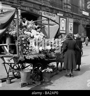 1950s, historique, de jour et une négociante féminine sert deux clientes à son stand de fleurs en plein air dans le Cadet, Opéra, Paris, France. Banque D'Images