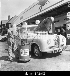 1950s, un préposé de station-service en uniforme donnant une voiture de l'époque, une vidange d'huile à Osterley Motors sur la Great West Road A4 Londres Angleterre, Royaume-Uni. Banque D'Images