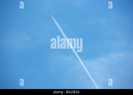 Traînée de condensation blanc à partir d'un Jet Comme il vole à travers un ciel bleu Banque D'Images