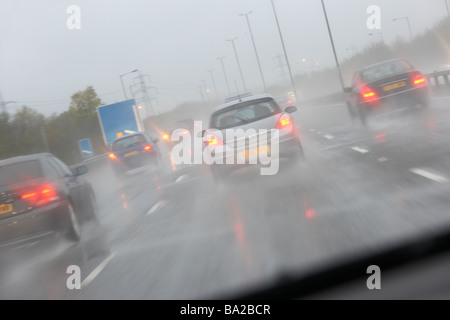 Les voitures qui circulent sur une route lissés de pluie Banque D'Images