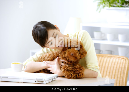 Young woman holding Toy Poodle sur table smiling Banque D'Images