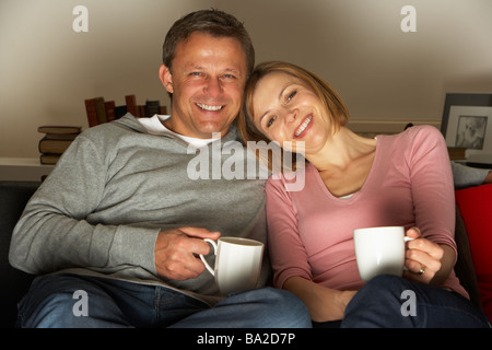 Avec deux tasses de café devant la télévision Banque D'Images