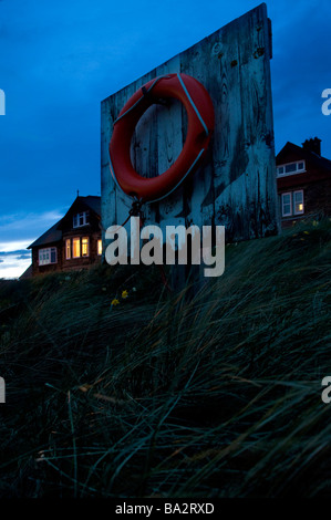 Bouée de sauvetage sur la plage au crépuscule Banque D'Images