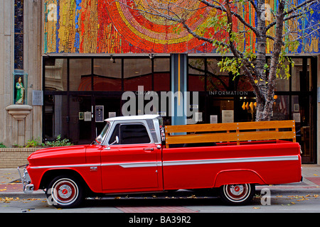 Chevy orange rouge vif camionnette avec lit en bois, balustrade en stationnement sur une rue de la ville. Banque D'Images