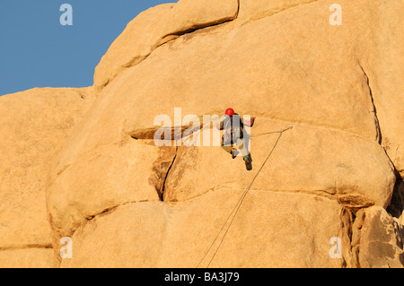 Un rock climber man se prépare à grimper une paroi de rochers pinnacle face Hidden Valley Joshua Tree National Park Banque D'Images