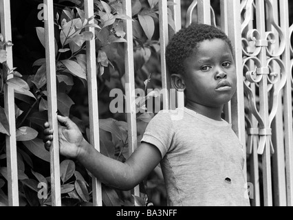 Années 70, photo en noir et blanc, les gens, la pauvreté, le garçon s'appuie contre une barre de fer, tatty teeshirt, âgés de 8 à 12 ans, au Brésil, Minas Gerais, Belo Horizonte Banque D'Images