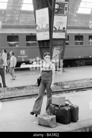 Années 70, photo en noir et blanc, de la gare, la gare centrale de Milan, jeune femme se tient sur la plate-forme et est en attente de la gare, valises, sac de voyage, de 25 à 30 ans, l'Italie, Lombardie, Milan Banque D'Images