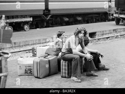 Années 70, photo en noir et blanc, de la gare, la gare centrale de Milan, le jeune garçon et sa petite sœur sur la plate-forme s'asseoir sur leurs bagages et attendre le train, âgés de 15 à 18 ans, de 10 à 14 ans, l'Italie, Lombardie, Milan Banque D'Images