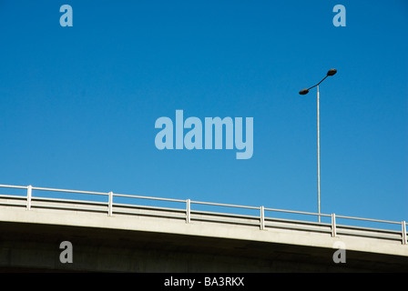 Un pont aérien avec rambarde et lampost contre un ciel bleu clair Banque D'Images