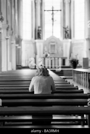 Années 1980, photo en noir et blanc, la religion, le christianisme, jeune femme s'agenouille sur un banc et prie, âgés de 30 à 35 ans, Elisabeth Banque D'Images