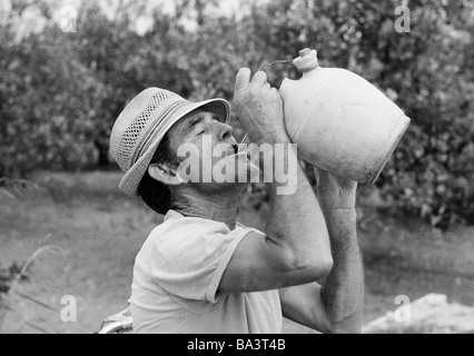 Années 70, photo en noir et blanc, de l'économie agraire, le travail de terrain, l'ouvrier agricole dans la Huerta de la province de Valence boit de l'eau d'un tankard, âgés de 40 à 50 ans, l'espagne, Valence Banque D'Images