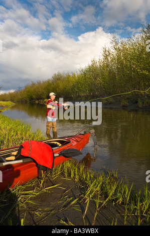 L'homme pêche de mouche sur le marécage de lapin à côté d'un lac kayak dans le sud de l'Alaska au cours de l'été Banque D'Images