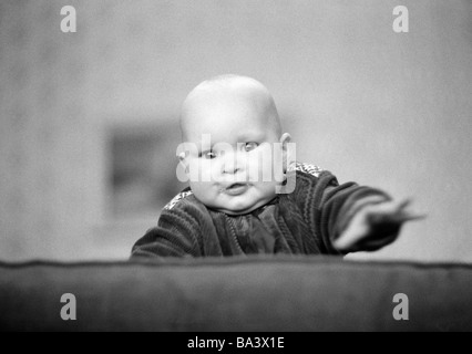 Annees 70 Photo En Noir Et Blanc Les Gens Les Enfants Bebe Essaie De Monter Le Dossier D Un Canape De 6 A 12 Mois A L Age De 1 Ans Christina Photo Stock Alamy