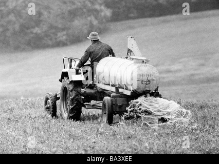 Années 70, photo en noir et blanc, de l'agriculture, la fertilisation, l'agriculteur avec un tracteur et un camion de miel sur un champ, Forêt Noire, Bade-Wurtemberg Banque D'Images