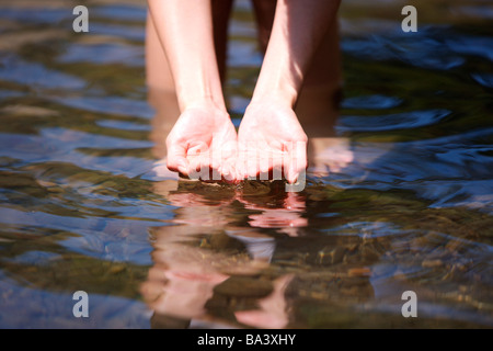 Femme debout dans l'eau de la rivière au creux des mains Banque D'Images