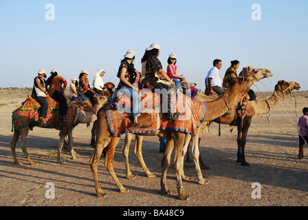 Les touristes prêts à monter des chameaux, sunset point, Jaisalmer, Rajasthan, Inde. Banque D'Images