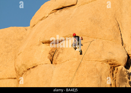 Un rock climber man se prépare à grimper une paroi de rochers pinnacle face Hidden Valley Joshua Tree National Park Banque D'Images