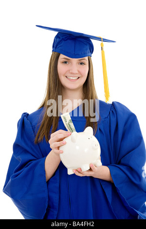 Caucasian teenager in Graduation Gown holding a piggy bank on white background Banque D'Images