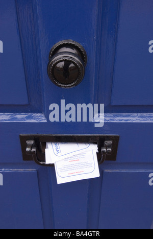 Dépliants de courrier indésirable qui sort d'une boîte aux lettres de la publicité peut-être une maison vide pour les cambrioleurs Banque D'Images