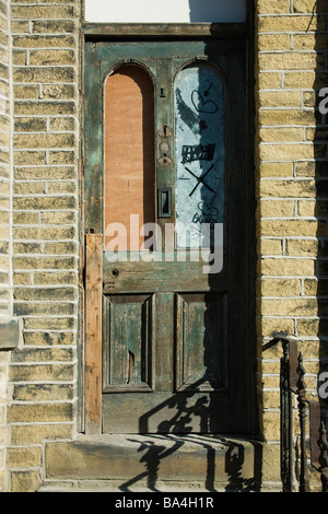 Une maison victorienne porte qui est à moitié fermés et dans un mauvais état à Halifax, Yorkshire Banque D'Images