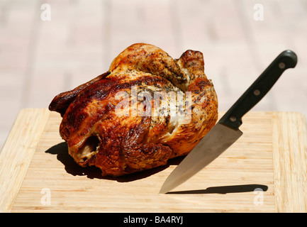 Poulet entier poivre citron sur planche en bois avec un couteau Banque D'Images