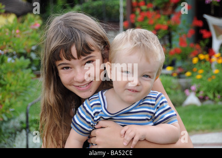 Français brune jeune fille épouse son très fair-haired boy bébé cousin allemand. Le tenant dans ses bras les deux sourire heureux Banque D'Images