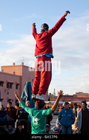 Acrobates locaux effectuant des acrobaties gymniques aventureux audacieuse pour divertir les foules, la place Jemaa el Fna, Marrakech Banque D'Images