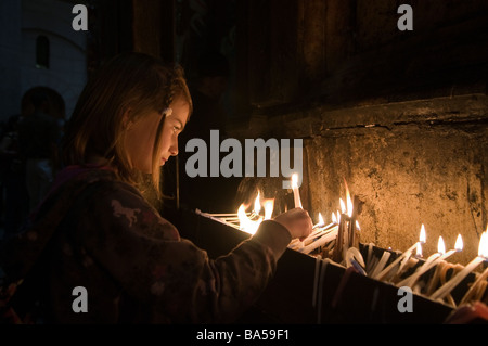 Une jeune fille allume des bougies à l'intérieur de l'Église du Saint-Sépulcre, dans le quartier chrétien de la vieille ville de Jérusalem-est Israël Banque D'Images