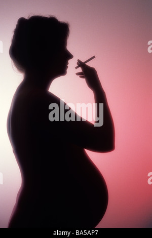 Silhouette femme fumer une cigarette pendant la grossesse studio rétroéclairé comportement malsain. Banque D'Images