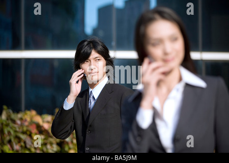 Portrait à l'avant à l'aide de l'accent sur téléphone cellulaire businessman standing with cell phone dans l'arrière-plan Banque D'Images