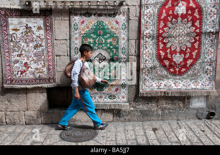 Israël Jérusalem Vieille ville Via Dolorosa Young boy carrying pain pitas wallking passé pendaison tapis Banque D'Images